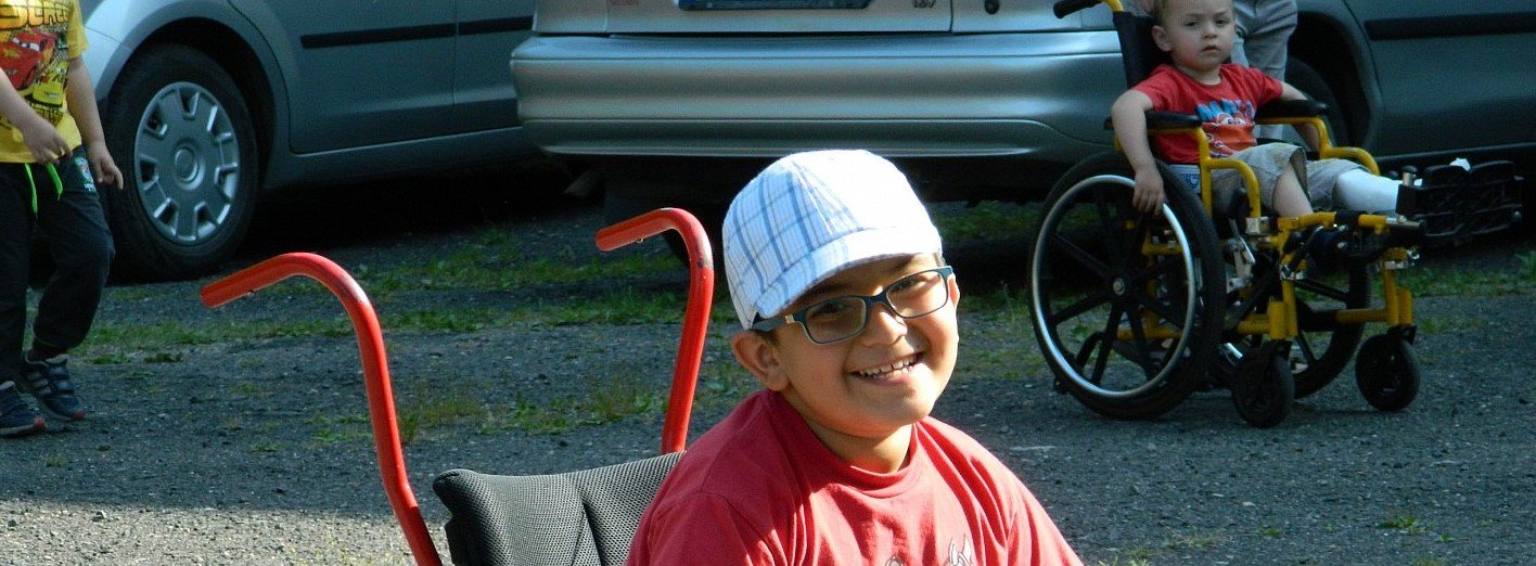 Lachende jongen in een rolstoel die hij van Caritatea heeft gekregen